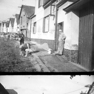 Here's a brief summary of the image: Man and child near houses, likely in a village setting.