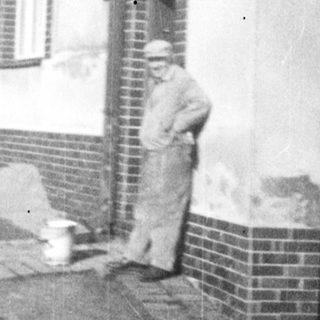 Here's a brief summary of the image: Man and child near houses, likely in a village setting.