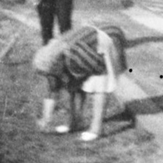 Here's a brief summary of the image: Man and child near houses, likely in a village setting.