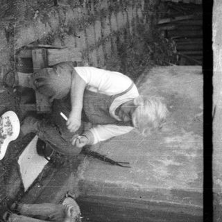 Two children playing with dolls near a doorway.