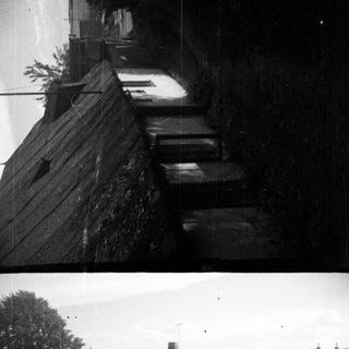 Here's a brief summary of the image: Black and white photo of a building with a thatched roof.