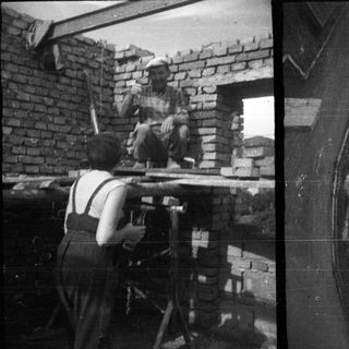 Here's a brief summary of the image: Bricklayer working on a building, photographed from below.