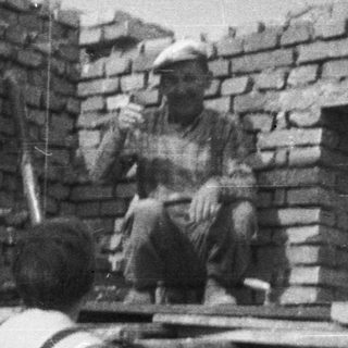 Here's a brief summary of the image: Bricklayer working on a building, photographed from below.