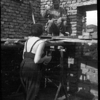 Here's a brief summary of the image: Bricklayer working on a building, photographed from below.