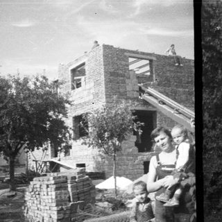 Here's a brief summary of the image: Family stands near a house under construction.