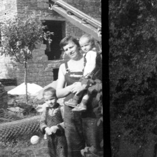 Here's a brief summary of the image: Family stands near a house under construction.