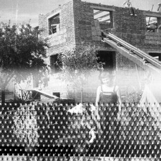 Construction site with a worker and unfinished brick building.