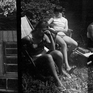 Here's a brief summary of the image: People relaxing outdoors, appearing to be in a wooded area.