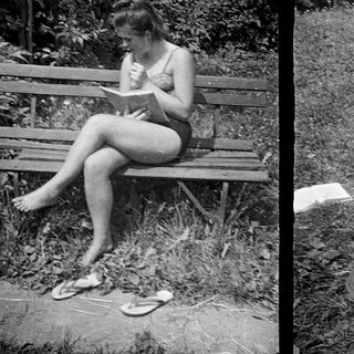 Here's a brief summary of the image: Two girls reading outdoors on a bench and chair.