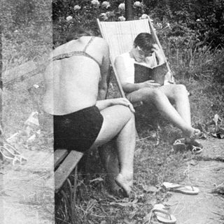 Two women playfully interact near a garden and chair.