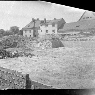 Construction site with a brick wall and building in background.