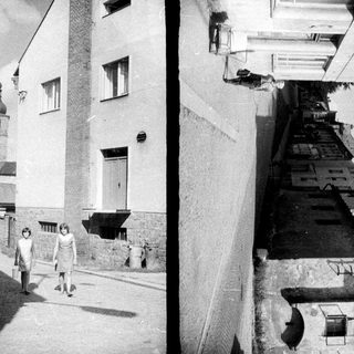 Here are a few brief summaries for each image: Image 1: Woman walking down a street, church visible in distance. Image