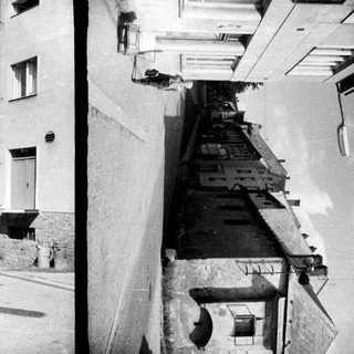 Here are a few brief summaries for each image: Image 1: Woman walking down a street, church visible in distance. Image