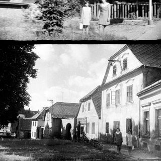 Here's a brief summary of what the image shows: Black and white photo of a street with houses and a person.