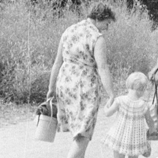 Family walking up a road with a stone wall.