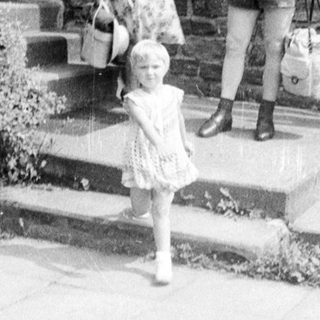 Family walking up a road with a stone wall.