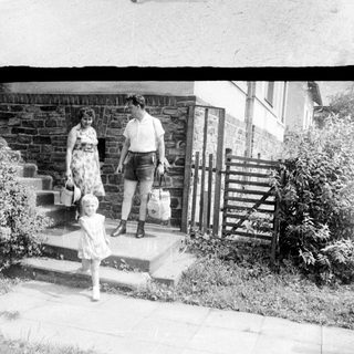 Family walking up a road with a stone wall.
