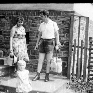 Family walking up a road with a stone wall.