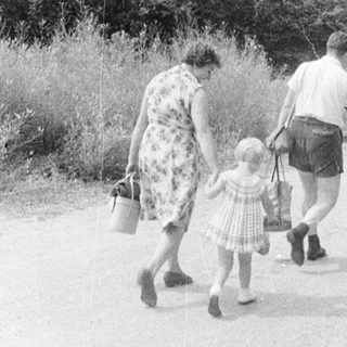 Family walking up a road with a stone wall.