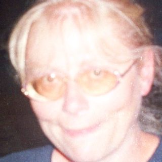 Woman stands in doorway with man visible behind her.