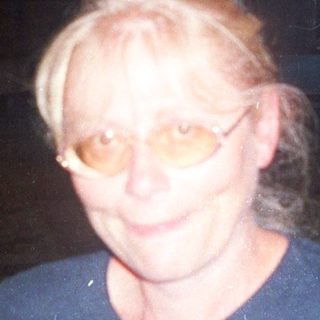 Woman stands in doorway with man visible behind her.