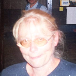 Woman stands in doorway with man visible behind her.