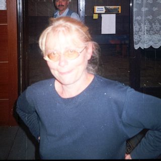 Woman stands in doorway with man visible behind her.