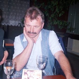 Here's a brief summary of the image: Couple seated at a table, man with his head down.