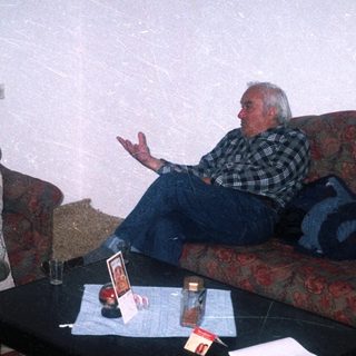 Two men seated on a patterned couch in a room.