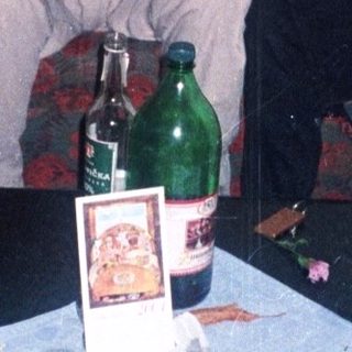 Two men seated on a sofa with a cluttered table.