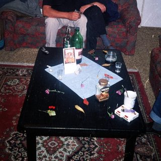 Two men seated on a sofa with a cluttered table.
