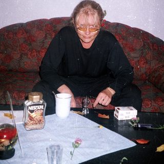 Woman seated on a couch with coffee and cigarettes.