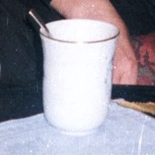 Woman seated on a couch with coffee and cigarettes.