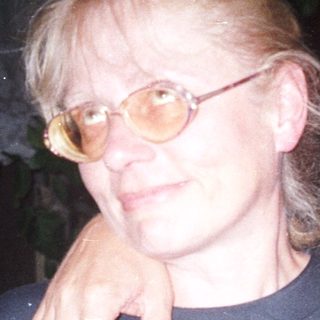 Two people are standing close together, arm around shoulder.