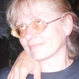 Two people are standing close together, arm around shoulder.