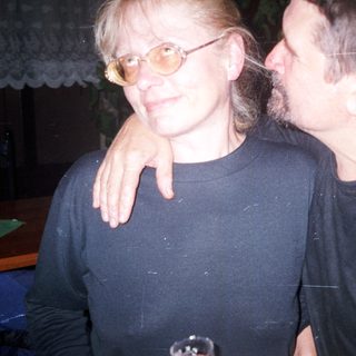 Two people are standing close together, arm around shoulder.