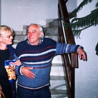 Elderly couple on stairs, holding sausages and potato chips.