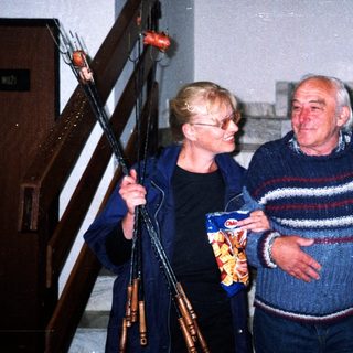 Elderly couple on stairs, holding sausages and potato chips.