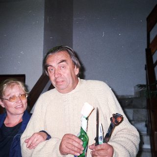 Man and woman holding items, standing near a staircase.
