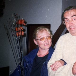 Man and woman holding items, standing near a staircase.