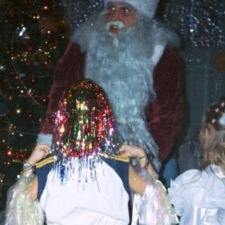 Children in costumes with Santa Claus at a festive event.