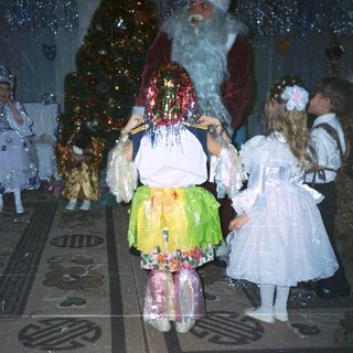 Children in costumes with Santa Claus at a festive event.