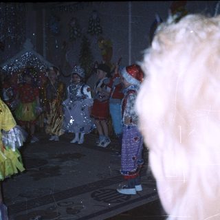 Children in costumes perform on a stage with decorations.