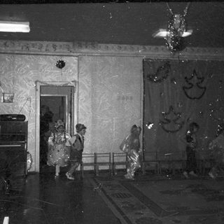 Children in costumes perform on a stage with audience.