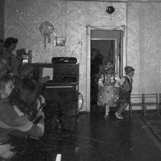 Children in costumes perform on a stage with audience.