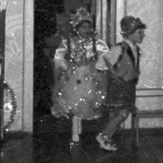 Children in costumes perform on a stage with audience.