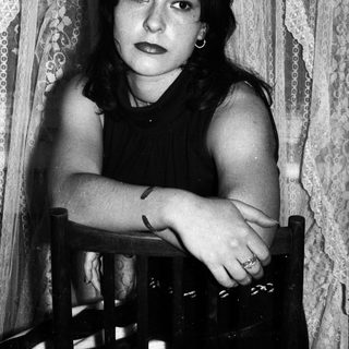 Black and white portrait of a young woman seated indoors.