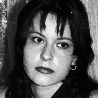 Black and white portrait of a young woman seated indoors.