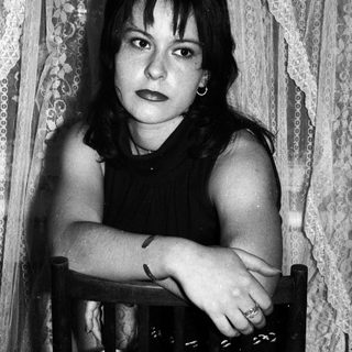 Black and white portrait of a young woman seated indoors.