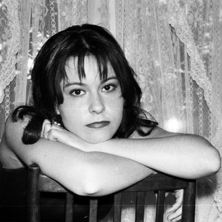 Black and white portrait of a young woman with arms crossed.